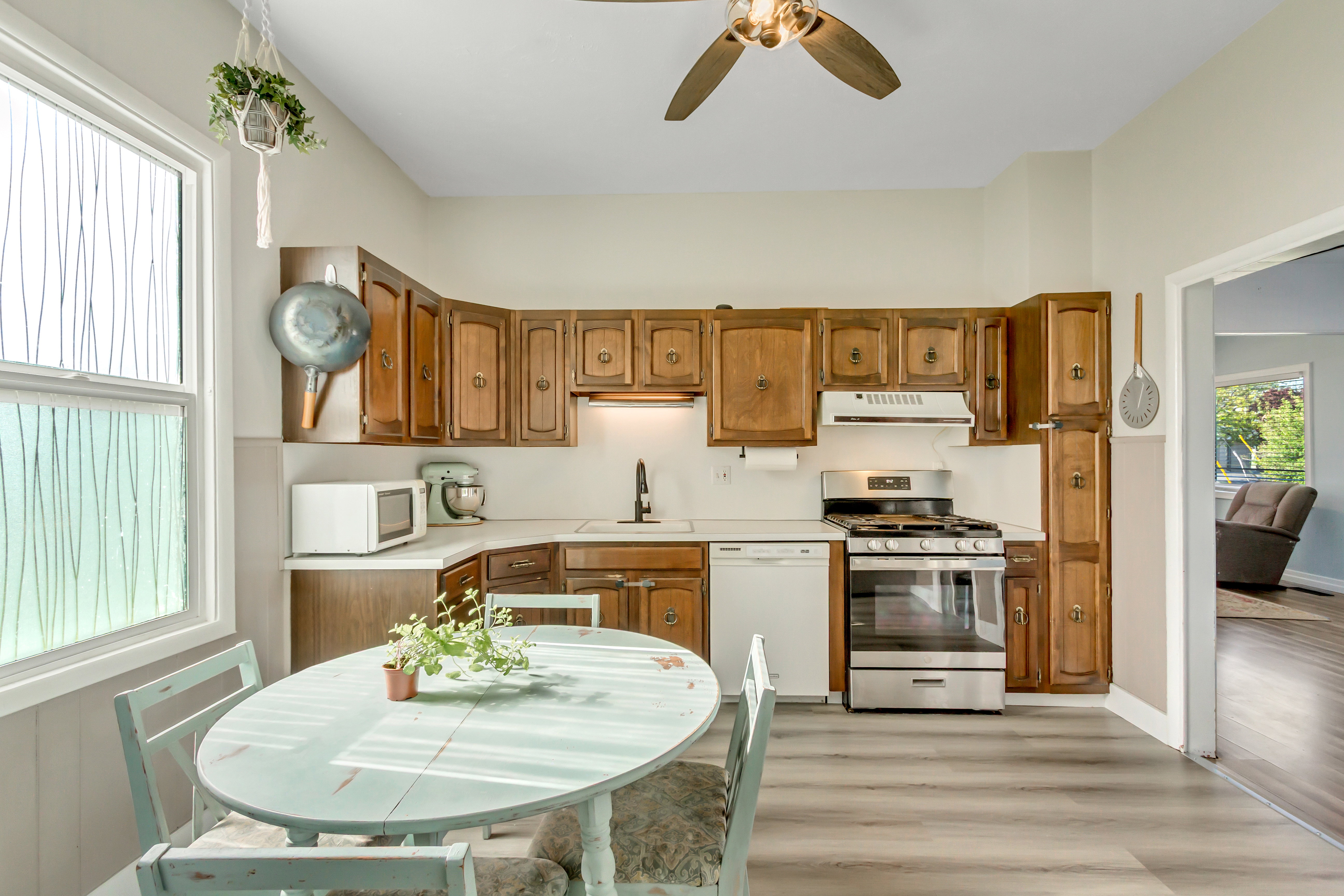 Kitchen with light countertops, white appliances, wood finish cabinetry, light wood-style floors, and ceiling fan