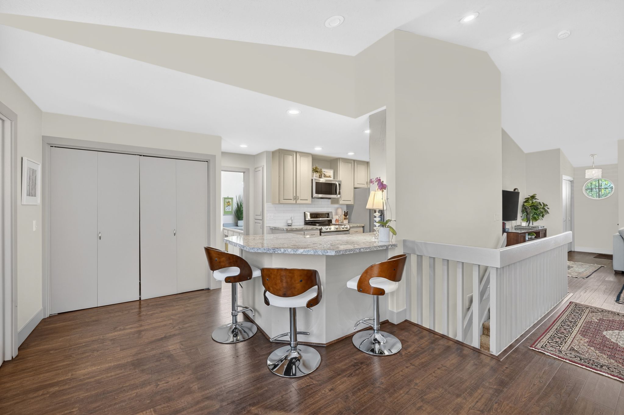 Kitchen featuring a kitchen breakfast bar, dark wood-type flooring, light stone counters, stainless steel appliances, and lofted ceiling