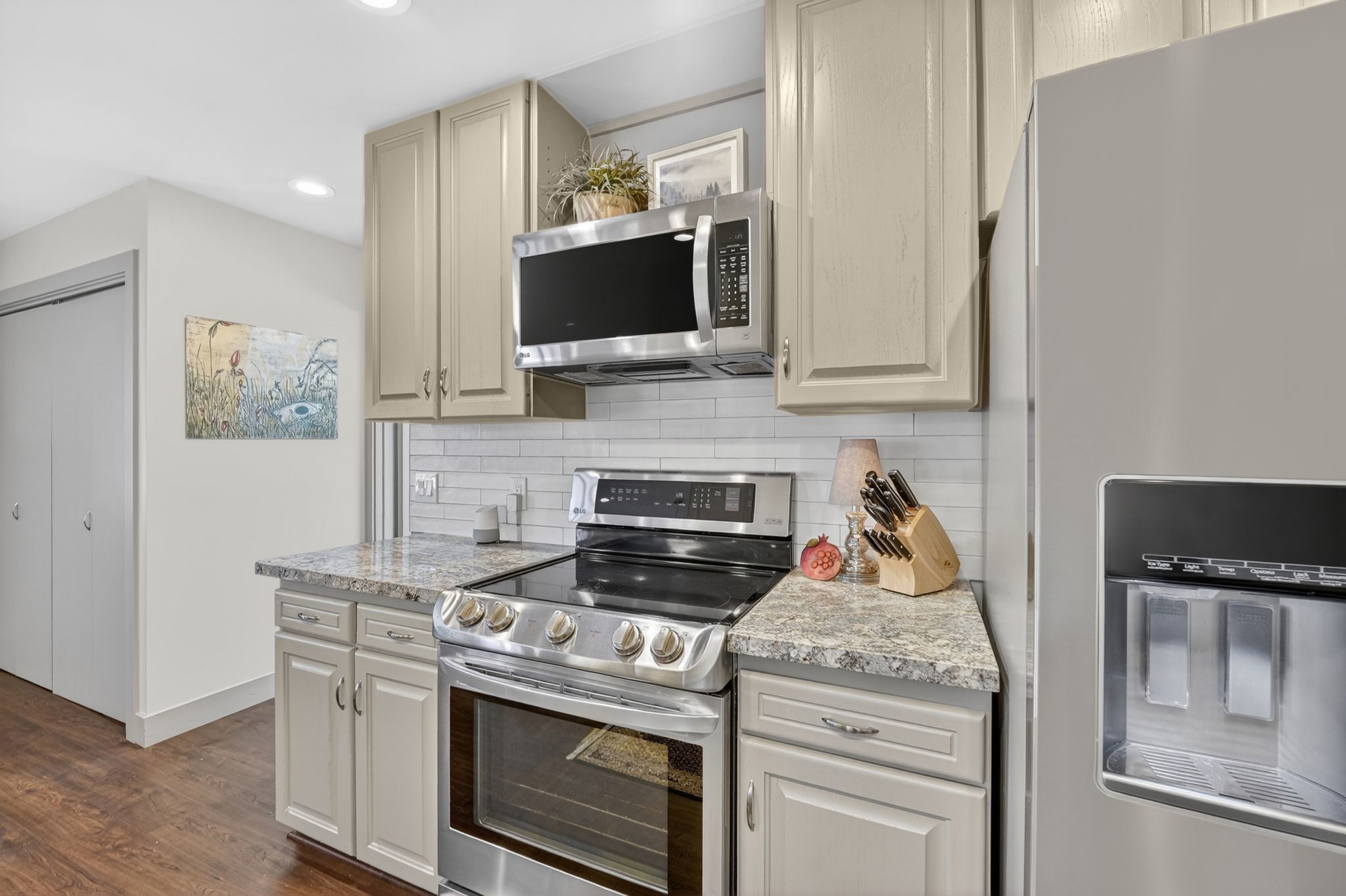 Kitchen featuring stainless steel appliances, dark wood-style flooring, recessed lighting, light stone counters, and decorative backsplash