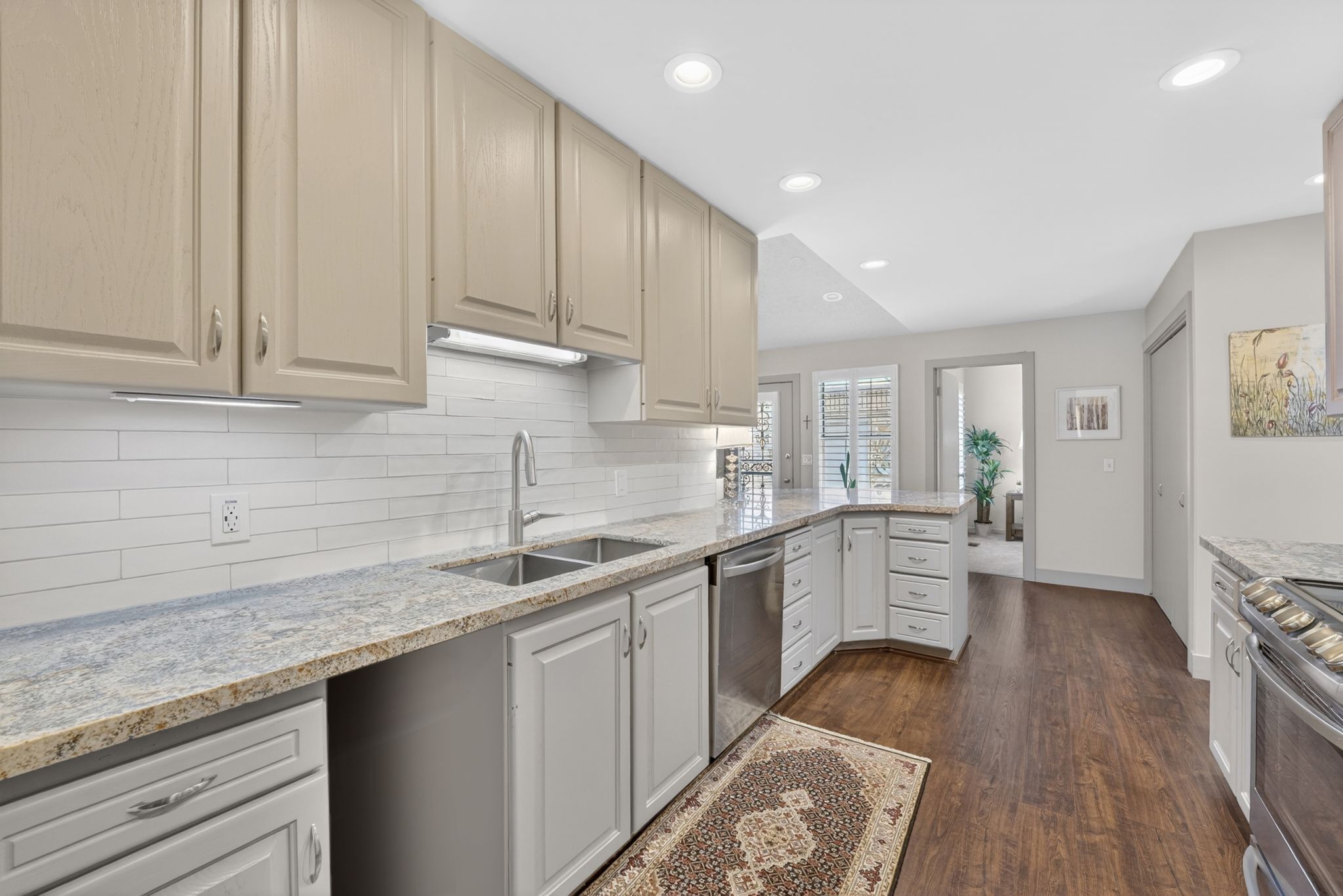 Kitchen featuring light stone counters, stainless steel appliances, dark wood-type flooring, recessed lighting, and a peninsula
