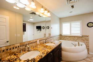 Full bath with double vanity and a garden tub