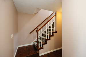 Stairs featuring wood finished floors and a textured ceiling