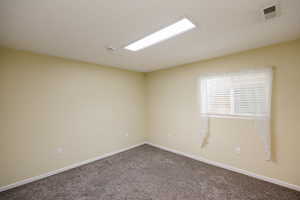Unfurnished room with baseboards and dark colored carpet