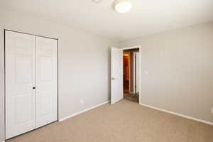 Unfurnished bedroom with light carpet and a closet