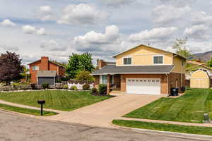 Traditional-style house with driveway, an attached garage, a front yard, brick siding, and board and batten siding