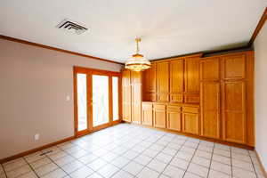 Spare room featuring crown molding, hanging lights, and light tile patterned floors