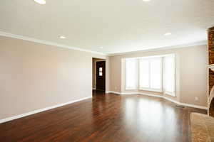 Unfurnished living room with dark wood-type flooring, ornamental molding, and recessed lighting