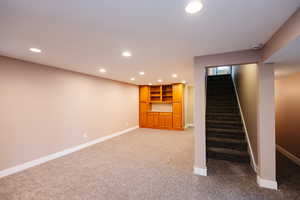 Finished basement with recessed lighting and light carpet
