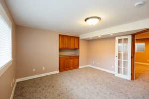 Empty room with light carpet and a smoke detector