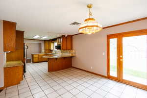 Kitchen with a peninsula, wood finish cabinets, a kitchen bar, light tile patterned flooring, and decorative backsplash