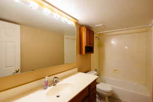 Bathroom with vanity, a textured ceiling, and bathtub / shower combination