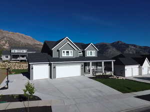 Contemporary home with a mountain backdrop, featuring a two-car garage, established front landscaping, and a covered porch entry
