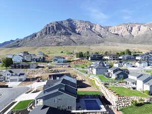 Modern gray exterior featuring a private swimming pool, terraced landscaping with rock retaining walls, and a mountain backdrop
