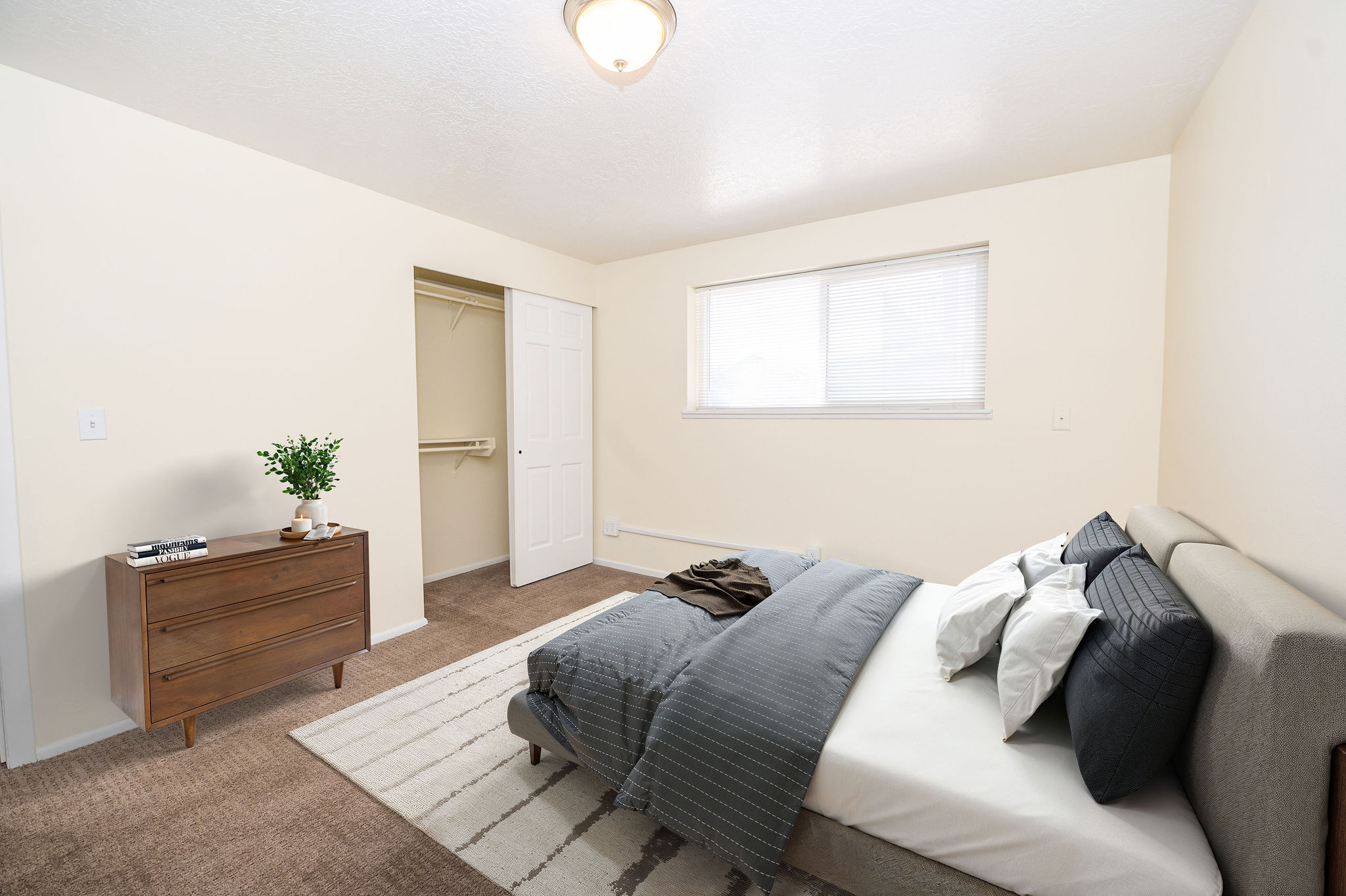 Bedroom featuring carpet flooring, a window with blinds, and a built-in closet with bi-fold doors