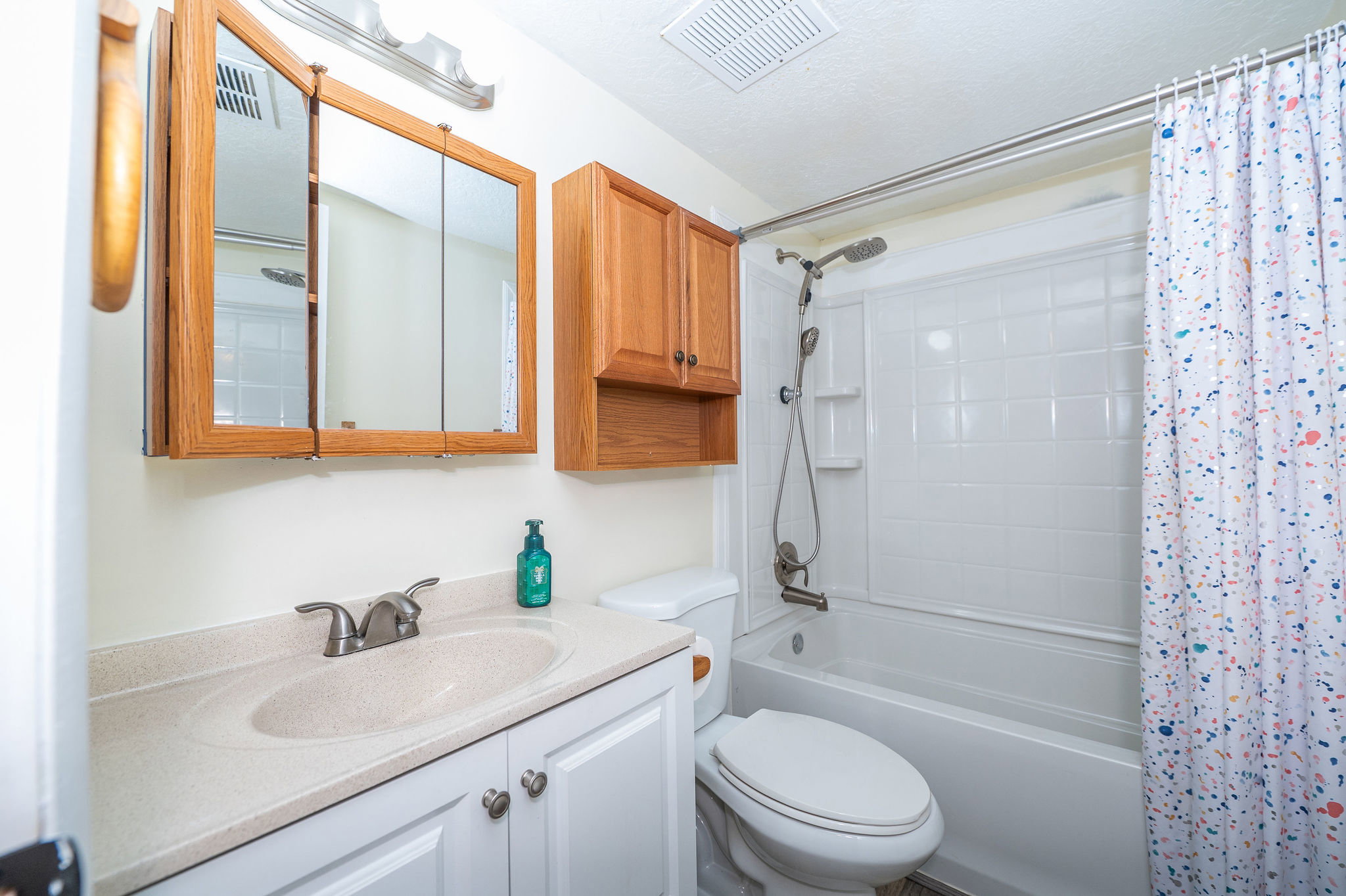 Full bathroom featuring a single vanity with an integrated sink, white cabinetry, and a mirrored medicine cabinet