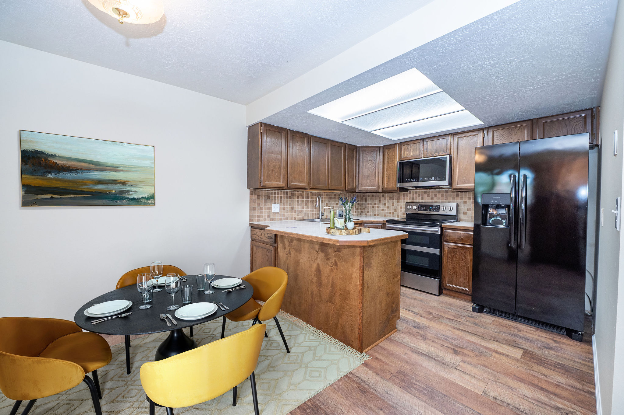 Kitchen featuring wood-finish flooring, wood cabinetry, a built-in microwave, and a black side-by-side refrigerator