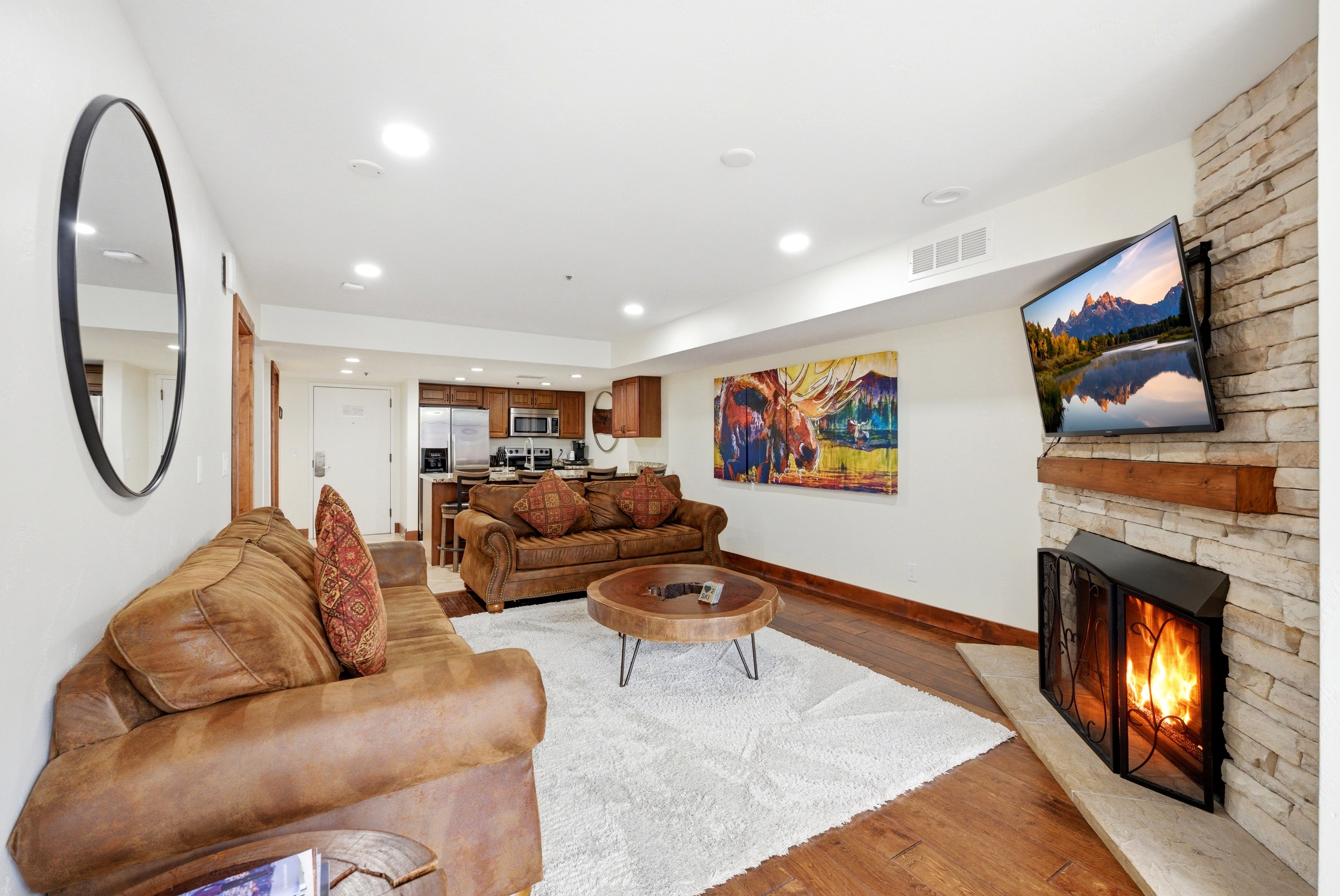 Living area featuring light wood-style floors, recessed lighting, and a stone fireplace