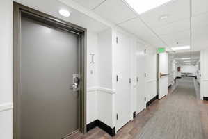 Corridor featuring a drop ceiling and dark wood-style flooring