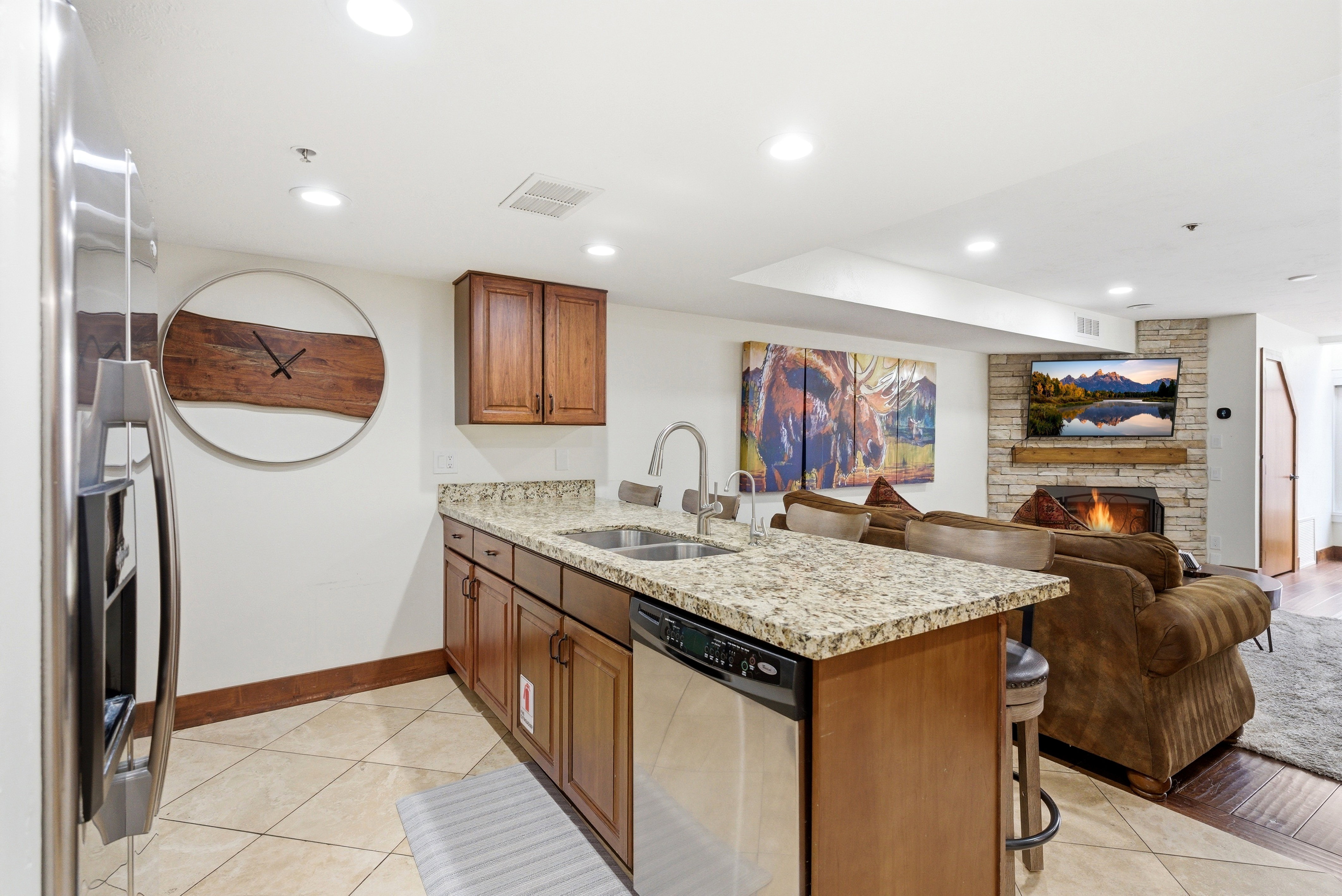 Kitchen with a peninsula, light stone counters, a fireplace, wood finish cabinets, and a kitchen breakfast bar