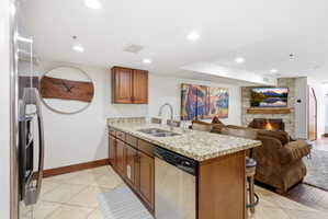 Kitchen with a peninsula, light stone counters, a fireplace, wood finish cabinets, and a kitchen breakfast bar