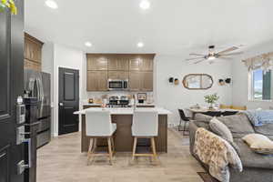 Kitchen with open floor plan, an island with sink, recessed lighting, light wood-style floors, and a kitchen bar