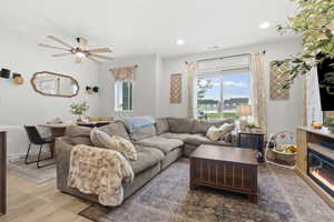 Living room with wood finished floors, a ceiling fan, recessed lighting, and a glass covered fireplace