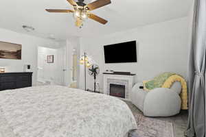 Carpeted bedroom featuring a brick fireplace and a ceiling fan