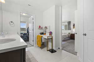 Ensuite bathroom featuring light carpet, double vanity, and healthy amount of natural light