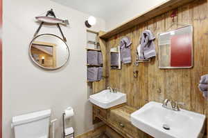 Half bathroom featuring wood walls and two sinks