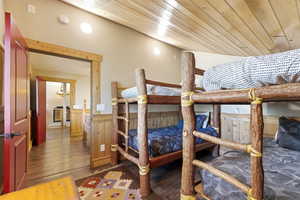Bedroom featuring wainscoting, dark wood-style floors, wood ceiling, and wood walls