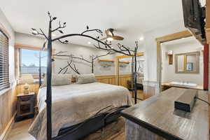 Bedroom with wooden walls, a wainscoted wall, and wood finished floors