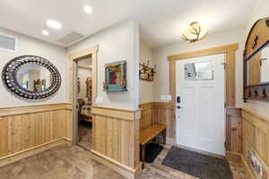 Foyer entrance featuring wood walls, wainscoting, wood-type flooring, and recessed lighting