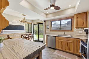 Kitchen featuring stainless steel appliances, light countertops, healthy amount of natural light, a raised ceiling, and a chandelier