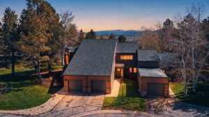 View of front of property featuring a front lawn, stone siding, a mountain view, and concrete driveway