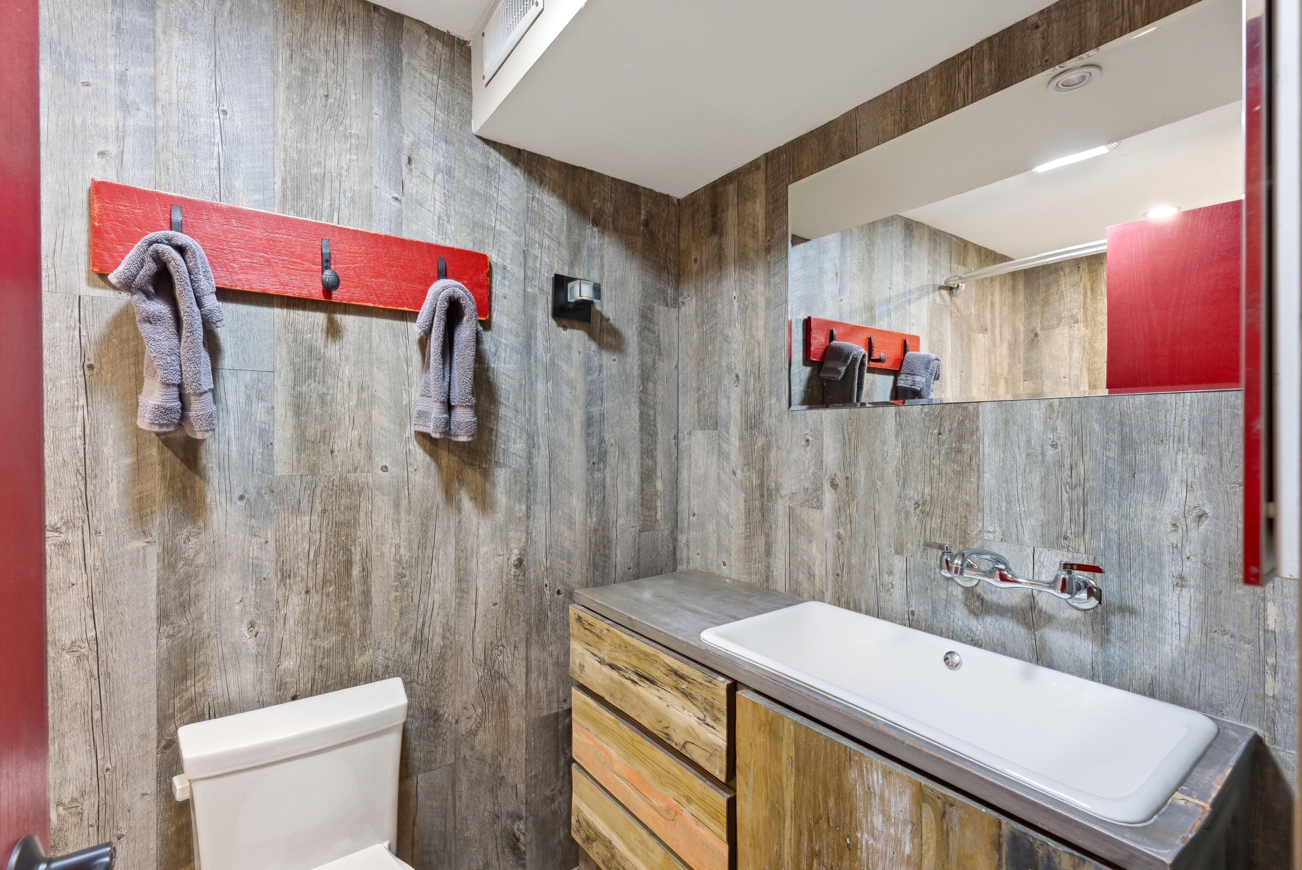 Full bath with vanity and wood walls