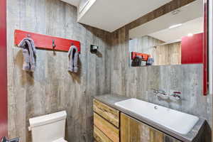 Full bath with vanity and wood walls