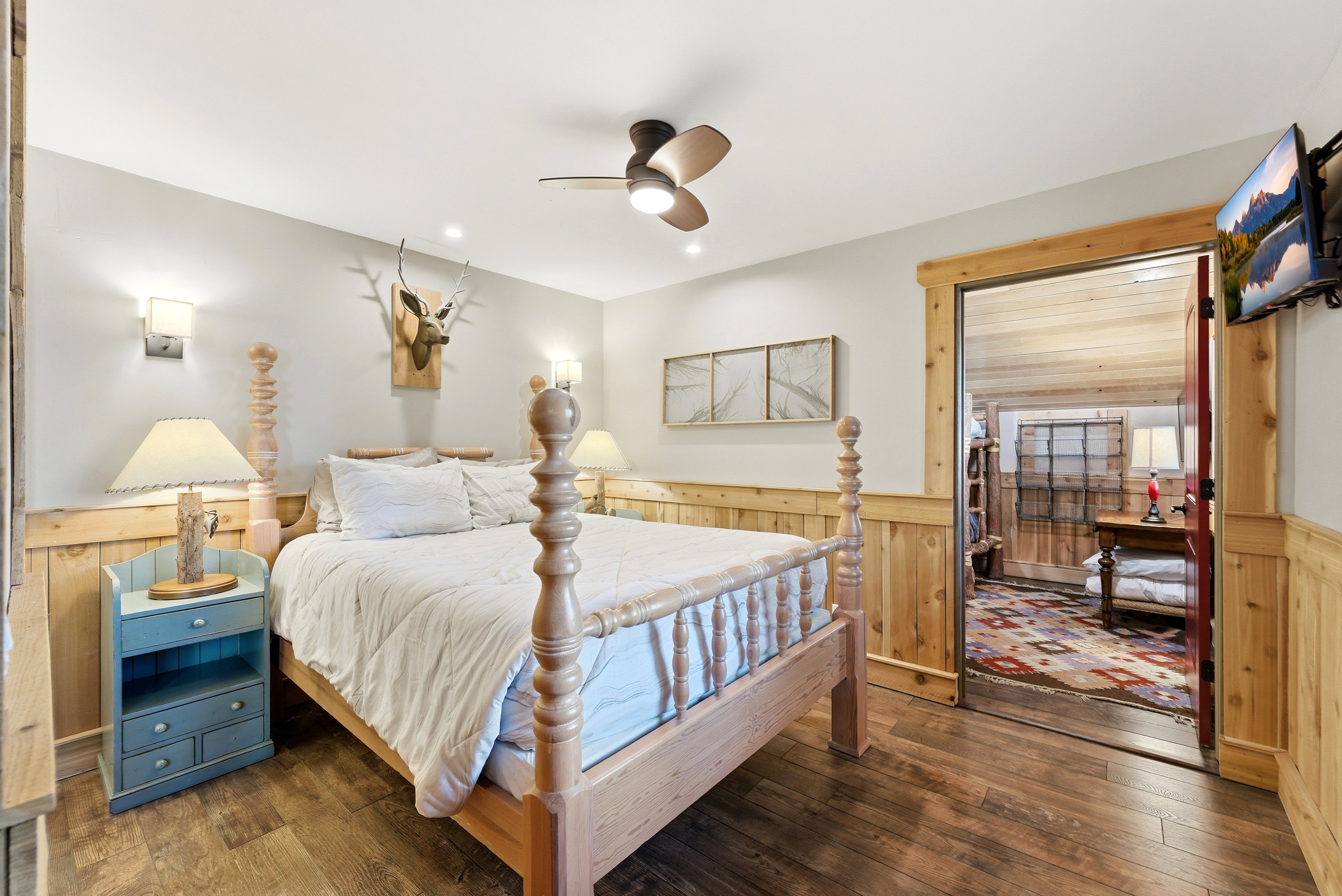 Bedroom featuring hardwood / wood-style floors, ceiling fan, wainscoting, and wood walls