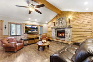 Living area featuring wood walls, wainscoting, beam ceiling, hardwood / wood-style flooring, and a fireplace