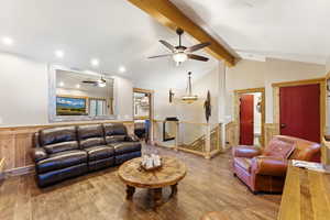 Living area with a wainscoted wall, hardwood / wood-style floors, wood walls, and a ceiling fan