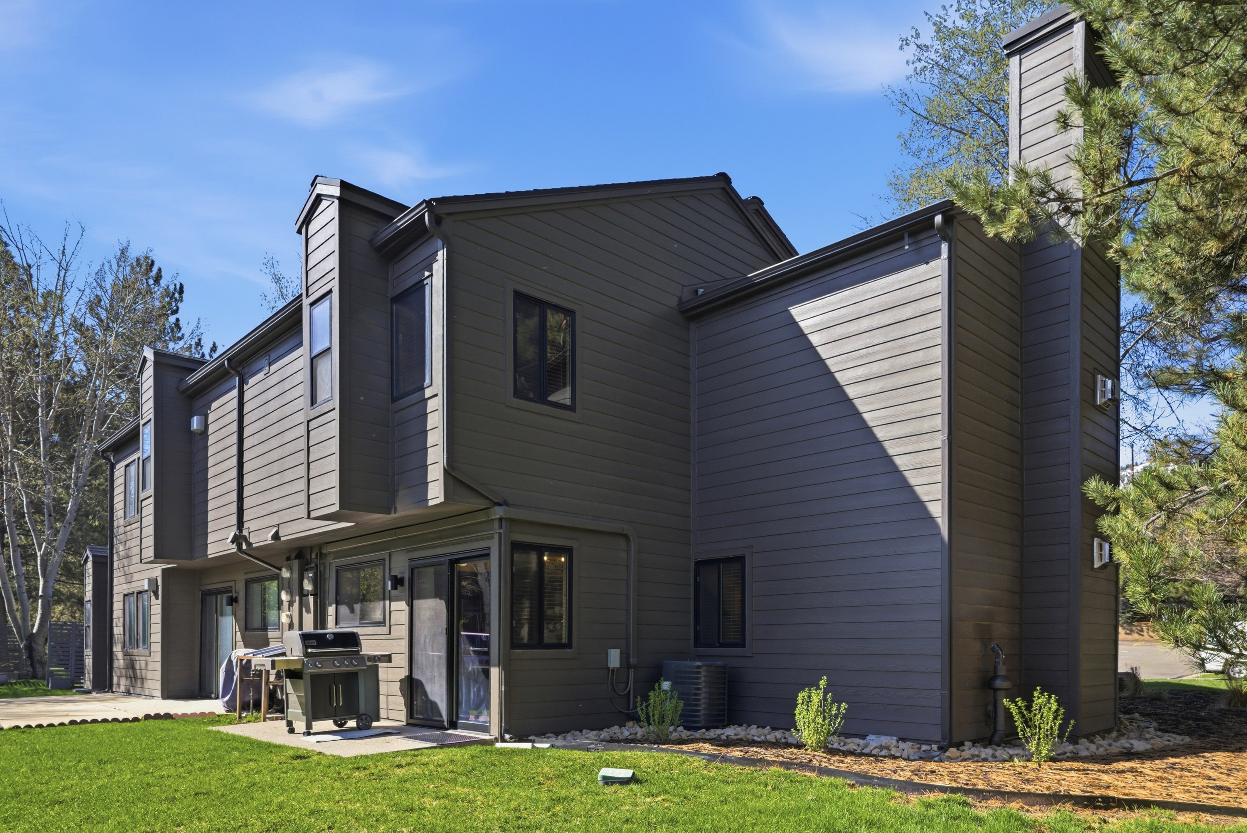 Back of house with a chimney, a lawn, and a patio area