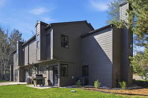 Back of house with a chimney, a lawn, and a patio area