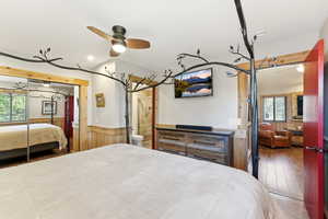 Bedroom with wood-type flooring, a ceiling fan, a closet, and wood walls