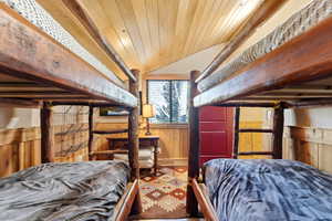 Bedroom with a vaulted wooden ceiling and wood walls