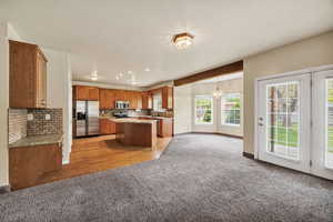 Kitchen featuring light carpet, stainless steel appliances, a center island, open floor plan, and hanging lights