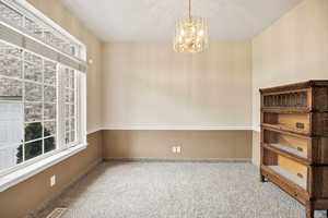 Unfurnished room featuring light carpet and a chandelier