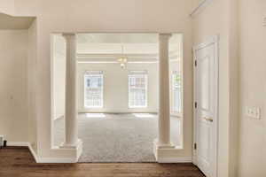 Foyer with decorative columns, wood finished floors, and a chandelier