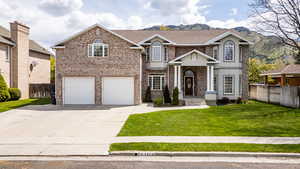 View of front of home featuring brick siding, concrete driveway, a garage, and a mountain view