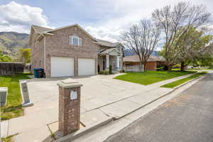 View of front of house featuring an attached garage, driveway, and brick siding
