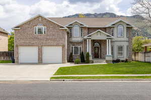 View of front of house featuring brick siding, driveway, a mountain view, and a garage