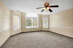 Spare room with a ceiling fan, light colored carpet, and a textured ceiling